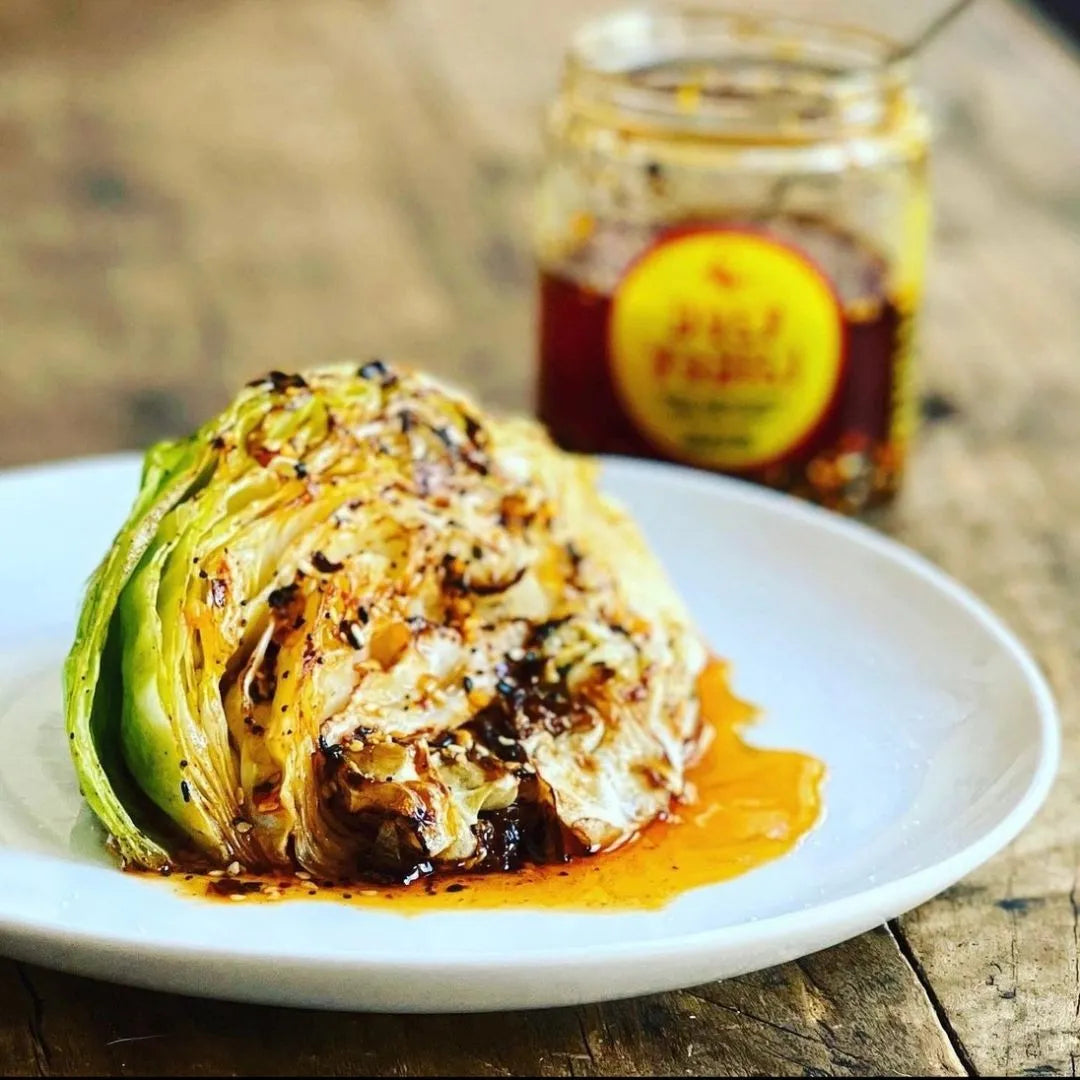 Stuffed cabbage leaf on a plate with a jar of sauce in the background