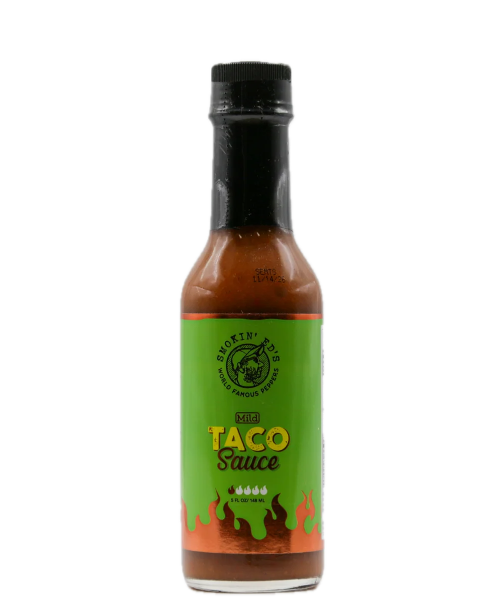 A bottle of Smokin Ed's Mild Hot Taco Sauce on a solid white background. The bottle contains reddish-brown sauce and features a bright green label