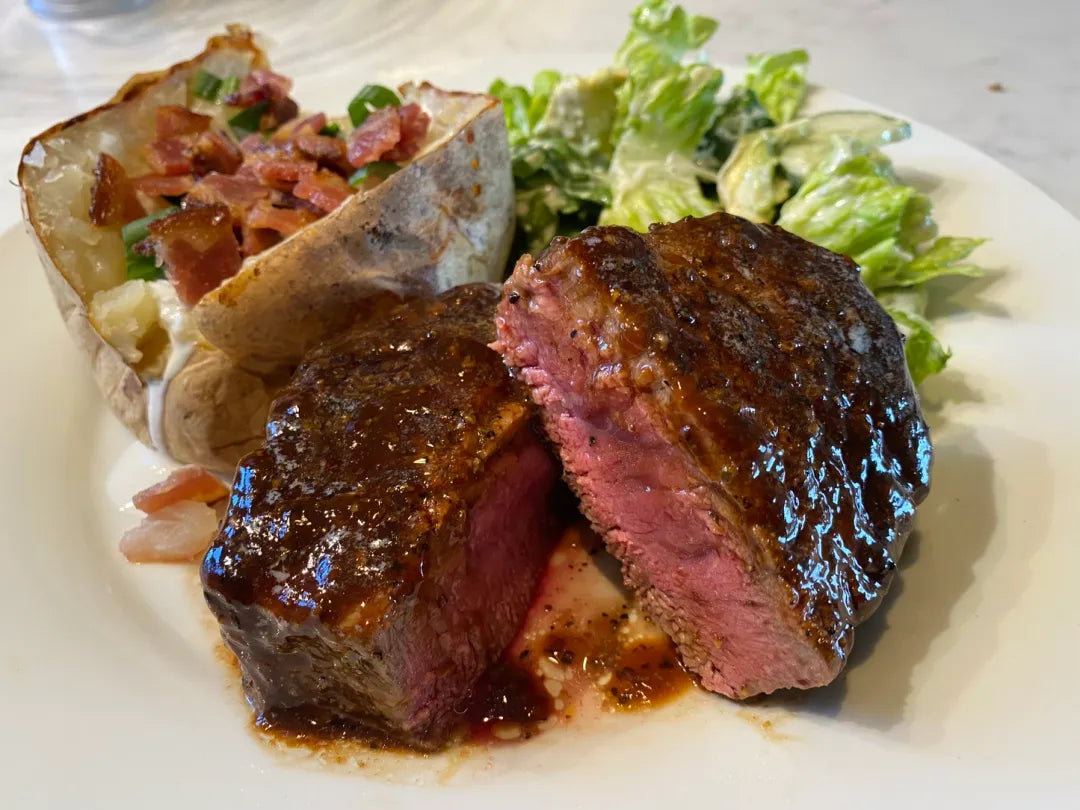Steak with a baked potato and salad on a white plate