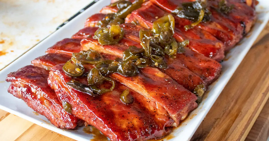 Plated dish of ribs with a green herb garnish on a wooden surface