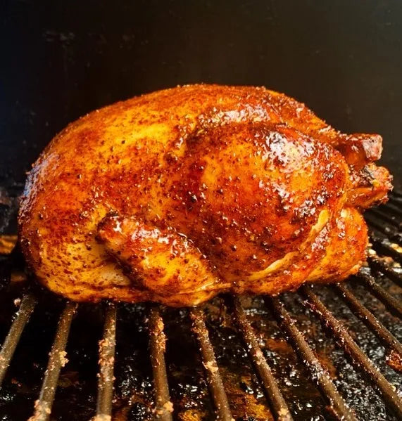 Grilled chicken on a barbecue grill with a dark background