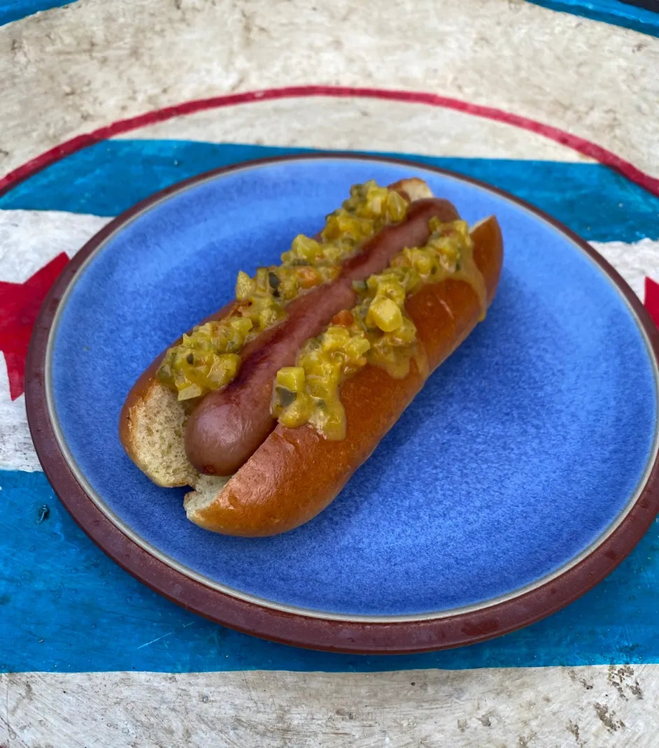 Hot dog with relish on a blue plate against a Chicago flag background