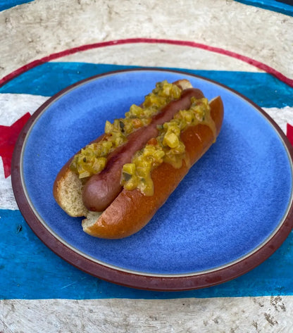 Hot dog with relish on a blue plate against a Chicago flag background
