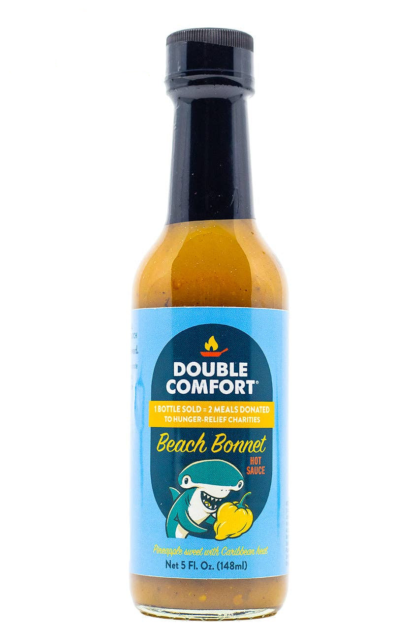 A bottle of Double Comfort Beach Bonnet hot sauce on a white background, featuring a blue label with a shark graphic.