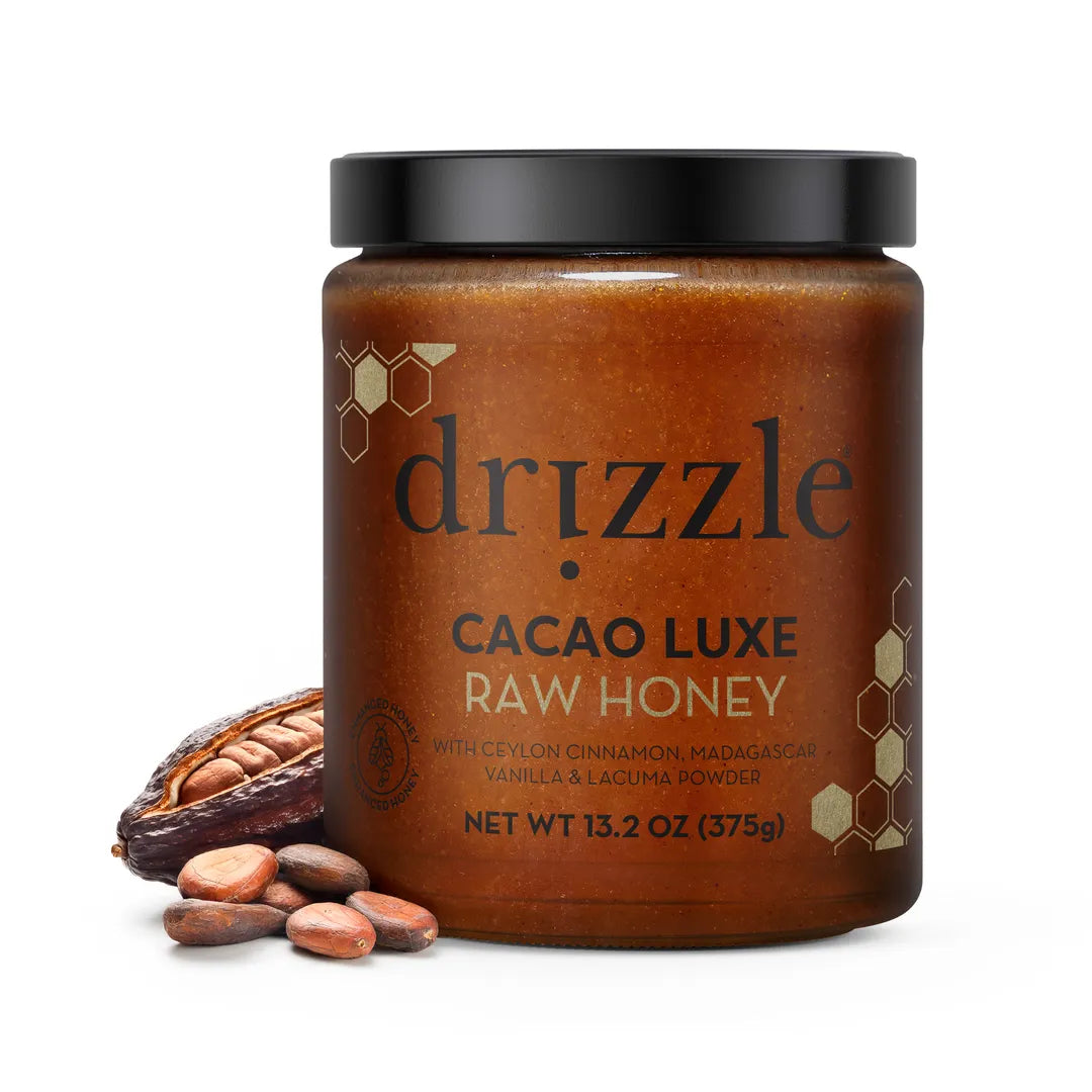 Jar of Drizzle Cacao Luxe Raw Honey with cocoa beans on a white background