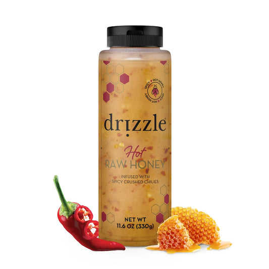 Drizzle hot raw honey bottle with chili peppers and honeycomb on a white background