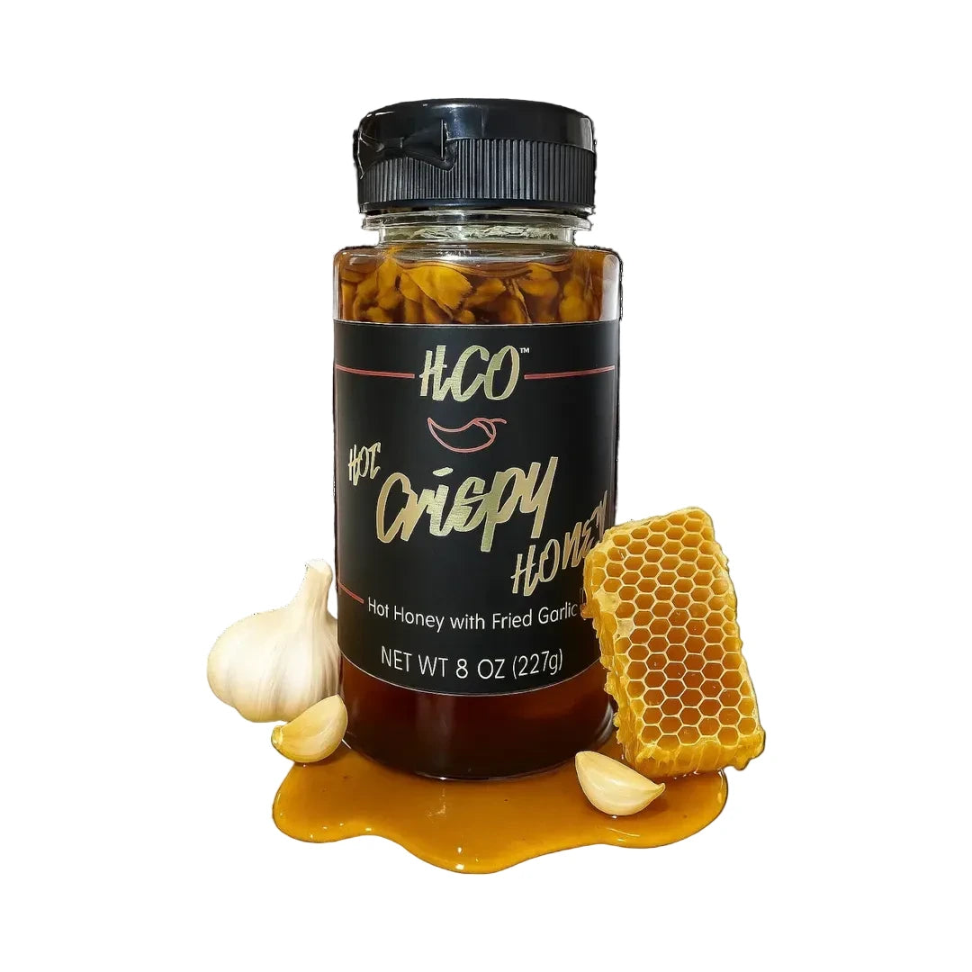 Jar of HCO Hot Crispy Honey with honeycomb and garlic on a white background