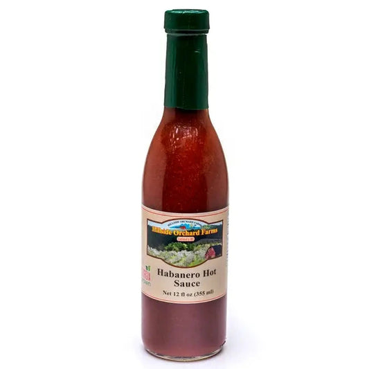 Bottle of Hillside Farms habanero hot sauce with a green cap on a white background
