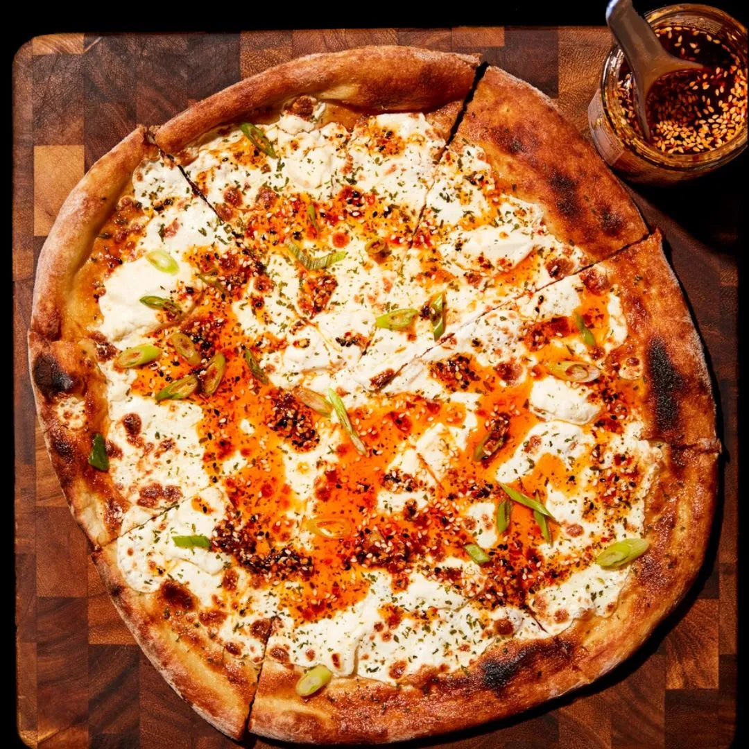 Pizza with cheese and green onions on a wooden cutting board