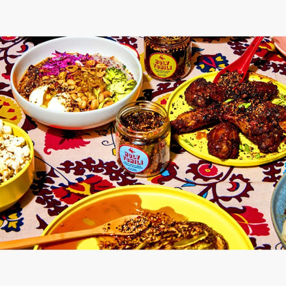 Diverse food items including a bowl of salad, plates of meat, and popcorn on a patterned tablecloth.