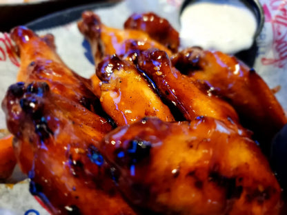 Braised chicken with a dark sauce on a plate with a side of white sauce.