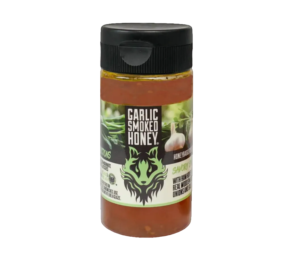 Jar of garlic smoked honey with a black lid on a white background