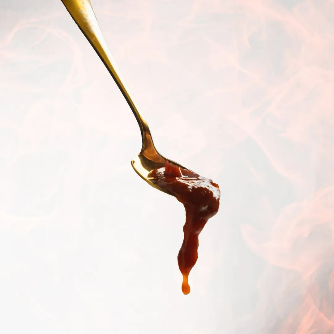 Spoon with caramel sauce dripping against a blurred background