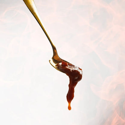 Spoon with caramel sauce dripping against a blurred background