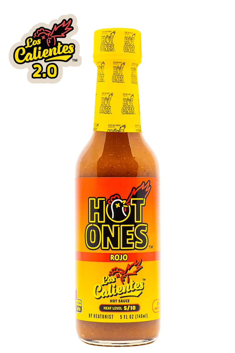A bottle of Los Calientes Rojo Hot Sauce against a white background, featuring a yellow and orange label with the brand logo and a red hot sauce liquid visible inside.