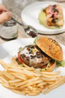 Hamburger with fries on a white plate with a side of salad.