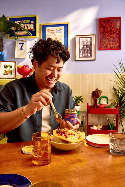 Person eating at a table with a bowl of food, a jar, and a glass of tea.