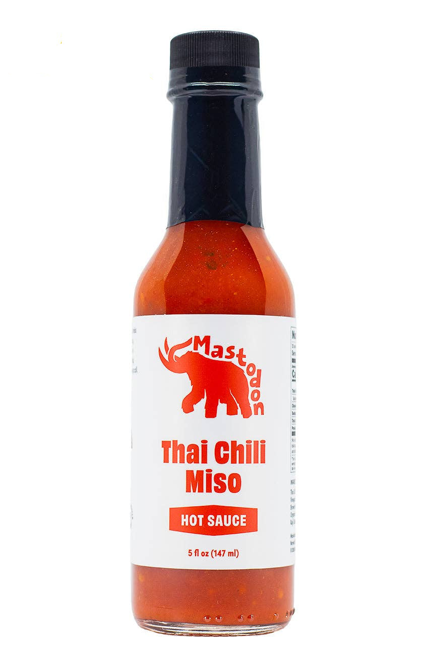 A bottle of Mastodon Thai Chili Miso hot sauce with a white label and red cap, shown on a white background.