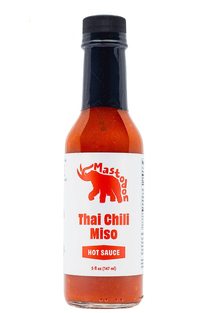 A bottle of Mastodon Thai Chili Miso hot sauce with a white label and red cap, shown on a white background.