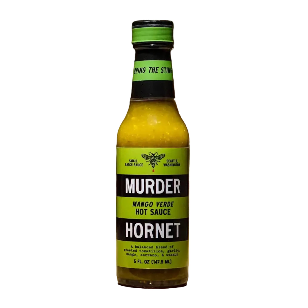 Bottle of Murder Hornet Mango Verde Hot Sauce on a wooden surface with a dark background