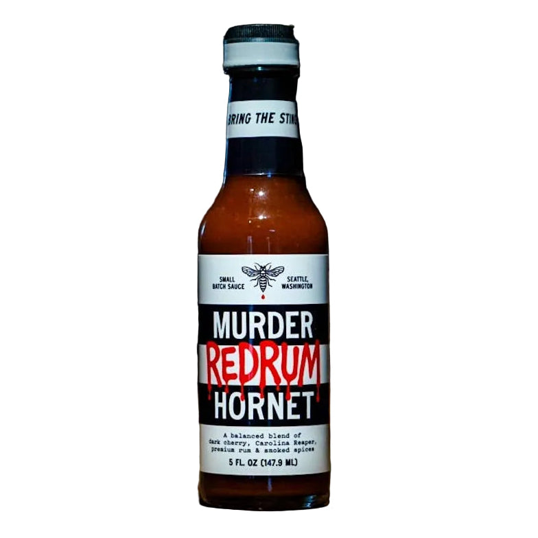Bottle of 'Murder Redrum Hornet' hot sauce on a wooden surface with a dark background
