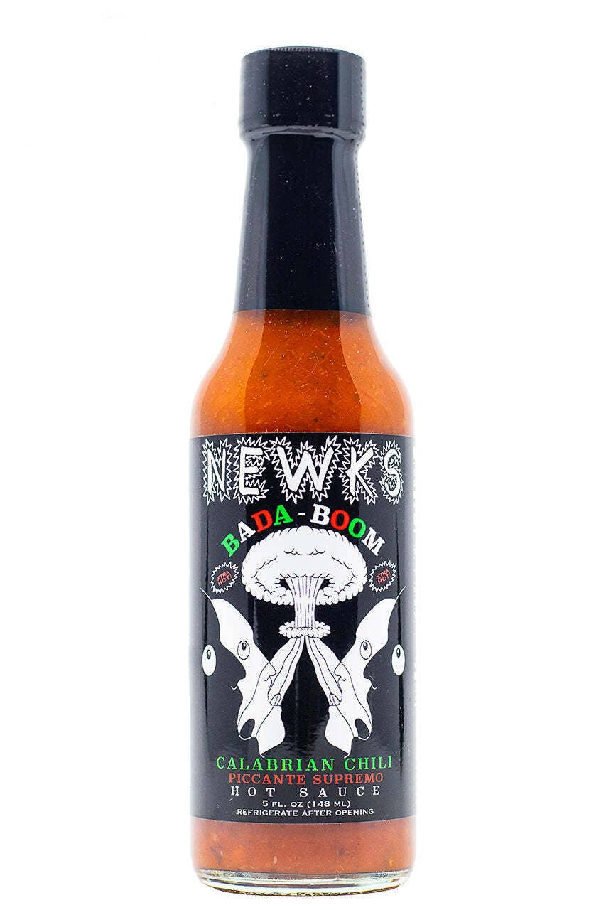 A bottle of Newks Bada-Boom Calabrian Chili Hot Sauce on a white background, featuring a black cap and a black label with white, green, and red text and graphics.