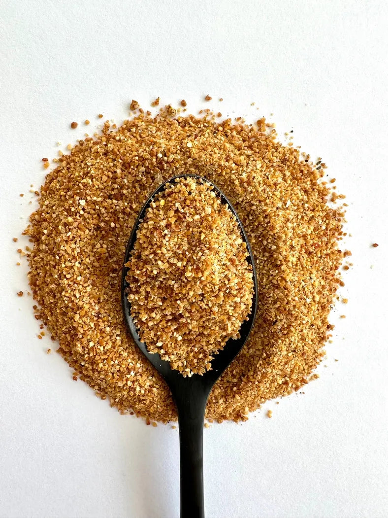 Black spoon filled with brown sugar on a white background