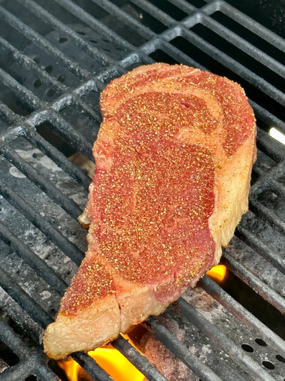 Steak on a grill with visible seasoning