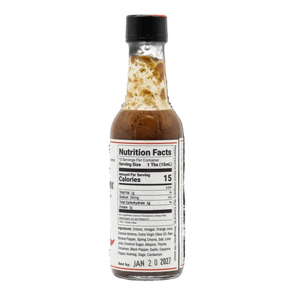 A small glass bottle of hot sauce with a black cap, showing the Nutrition Facts label on the front against a plain white background.