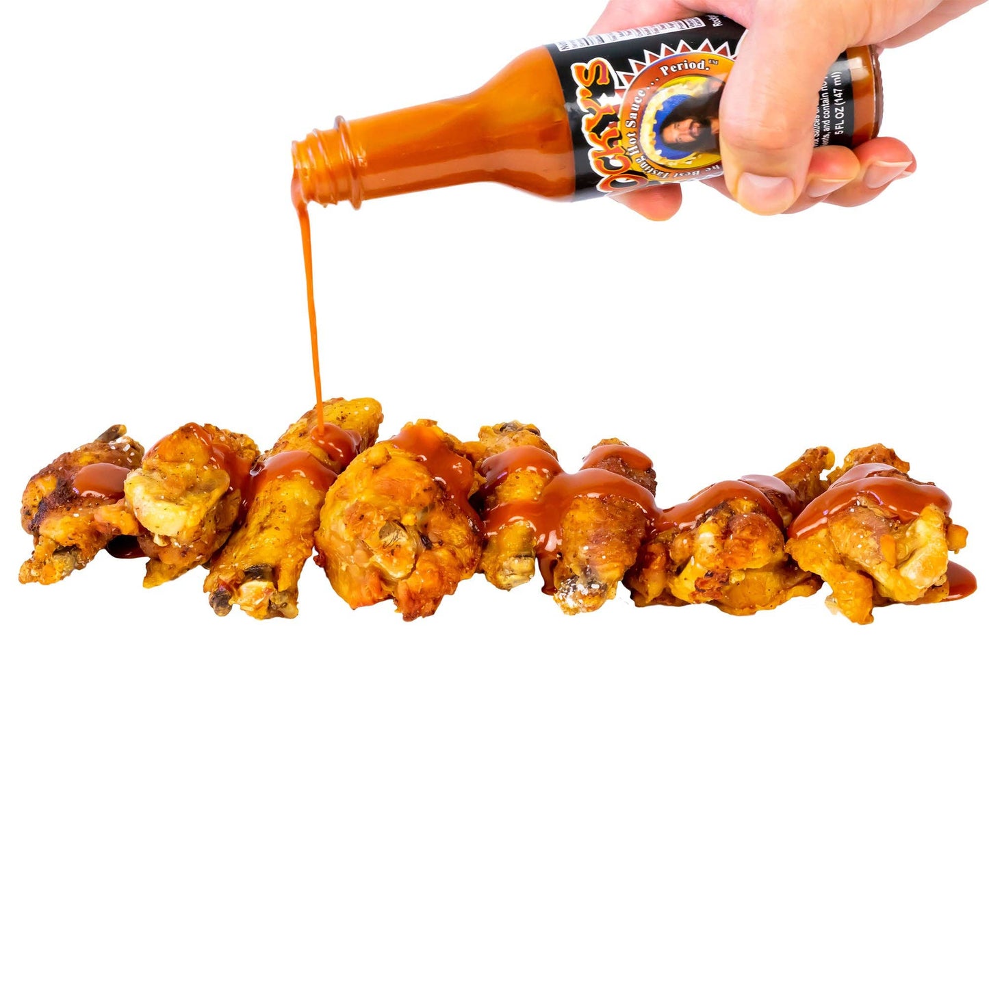 Rocky's Nashville hot sauce being poured onto a skewer of grilled chicken wings.