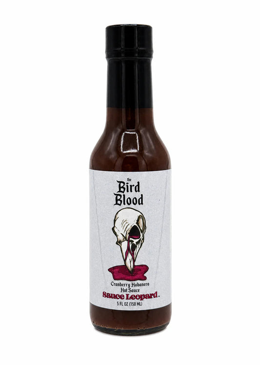 A bottle of Bird Blood Sauce Leopard hot sauce with a white label featuring a skull illustration and red sauce visible at the bottom, set against a plain white background.