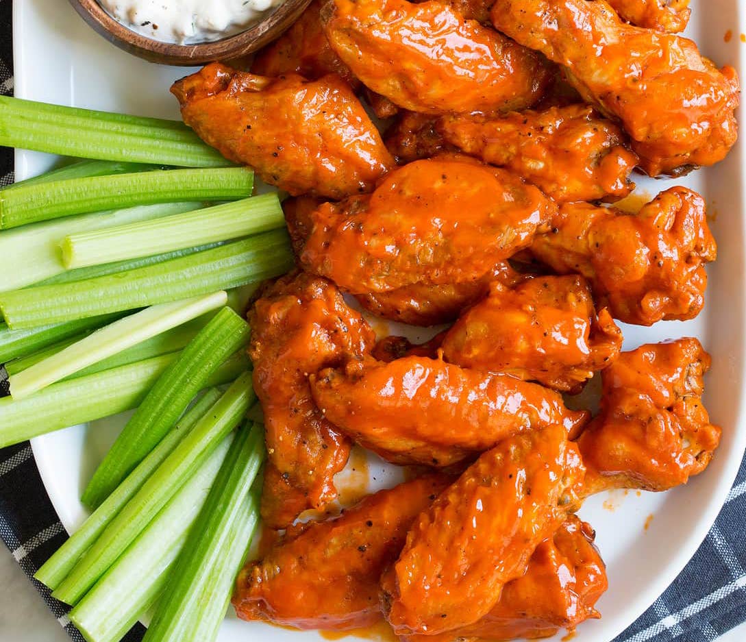 Platter of Buffalo wings with Saucy Mama spicy garlic hot sauce with celery sticks
