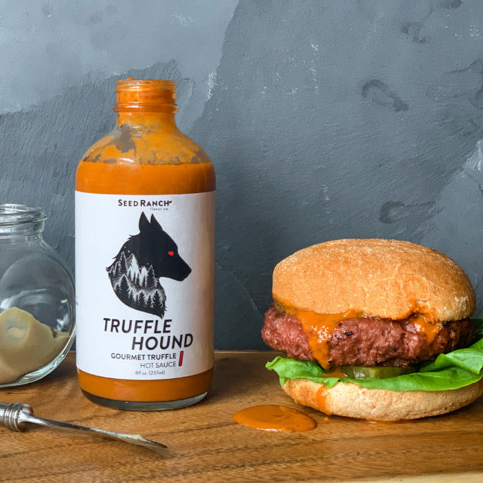 Truffle Hound hot sauce bottle with a burger on a wooden surface
