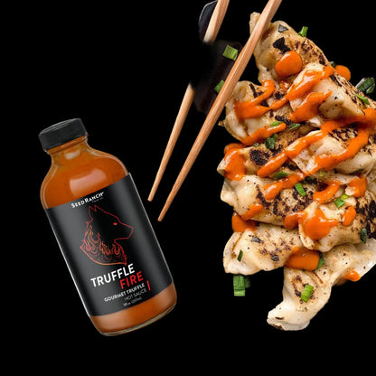 Bottle of Truffle Fire hot sauce next to a plate of food with truffle sauce.