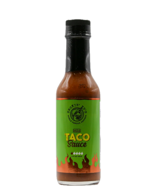A bottle of Smokin Ed's Mild Hot Taco Sauce on a solid white background. The bottle contains reddish-brown sauce and features a bright green label