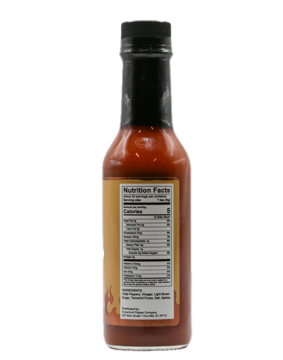 A bottle of hot sauce with a black cap and a tan label showing the Nutrition Facts panel, isolated on a white background.