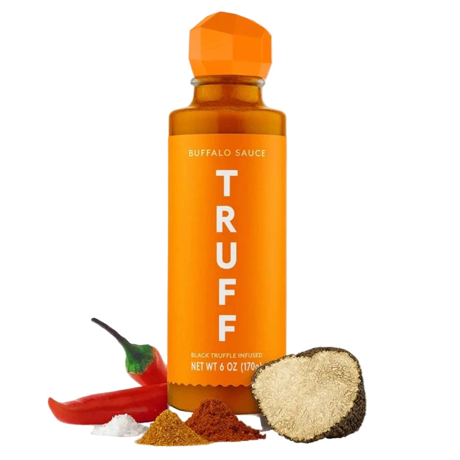 Orange bottle of TRUFF buffalo sauce with a pepper and truffle on a white background