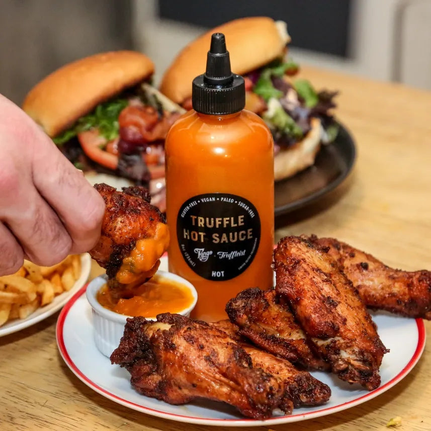 Bottle of Truffleist hot sauce with chicken wings