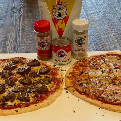 Two pizzas with various toppings and pizza-making ingredients on a wooden surface.