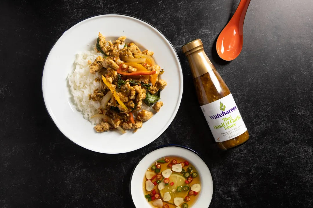 Plate of food with a bottle of sauce on a dark surface