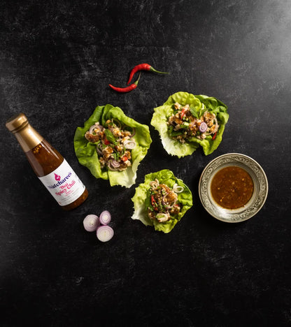 Lettuce wraps with a bottle of sauce on a dark surface
