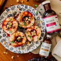 Platter of shrimp with a bottle of sauce on a wooden surface