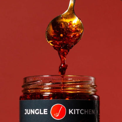 Spoon dripping honey into a jar with 'Jungle Kitchen' label on a red background