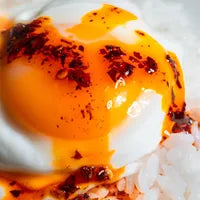 Close-up of a boiled egg with a runny yolk on a white background