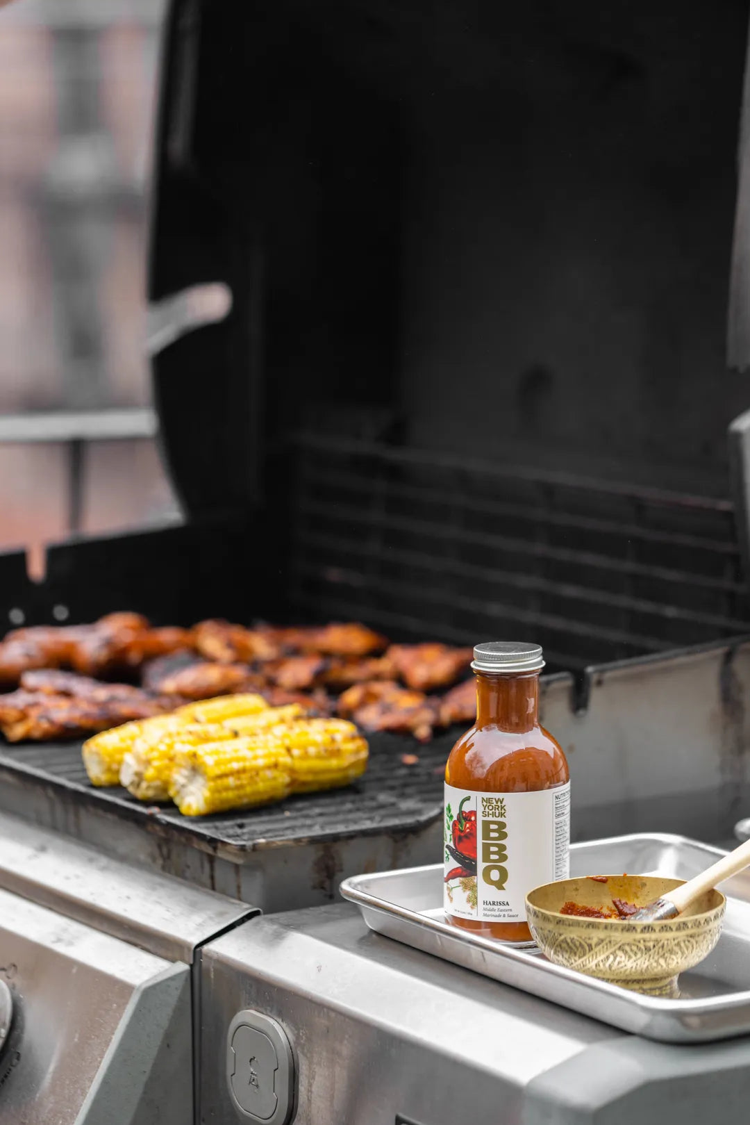 New York Shuk Harissa BBQ Sauce near a grill