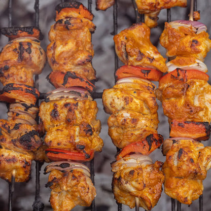 Skewers of grilled chicken and vegetables on a grill